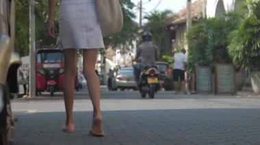 Avrupalı bir kız Sri Lanka 'da sessiz bir caddede yürüyor, ağır çekimde. Kasaba çevresindeki turizm kavramı