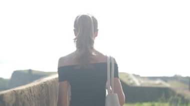 At kuyruklu bir kız dünya mirası sahasında yürüyor ve manzaranın tadını çıkarıyor, ağır çekimde. Tarihi bir ortamda seyahat kavramı