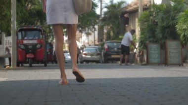 Avrupalı bir kız Sri Lanka 'da sessiz bir caddede yürüyor, ağır çekimde. Kasaba çevresindeki turizm kavramı
