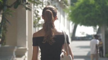 Avrupalı bir kız Sri Lanka 'da sessiz bir caddede yürüyor, ağır çekimde. Kasaba çevresindeki turizm kavramı