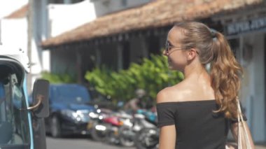Avrupalı bir kız Sri Lanka 'da sessiz bir caddede yürüyor, ağır çekimde. Kasaba çevresindeki turizm kavramı