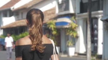 Avrupalı bir kız Sri Lanka 'da sessiz bir caddede yürüyor, ağır çekimde. Kasaba çevresindeki turizm kavramı