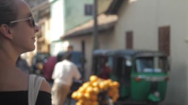 Avrupalı bir kız Sri Lanka 'da sessiz bir caddede yürüyor, ağır çekimde. Kasaba çevresindeki turizm kavramı
