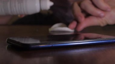 Antiseptikle akıllı telefona muhalif olan birinin yakın plan fotoğrafı.