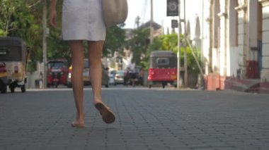 Avrupalı bir kız Sri Lanka 'da sessiz bir caddede yürüyor, ağır çekimde. Kasaba çevresindeki turizm kavramı