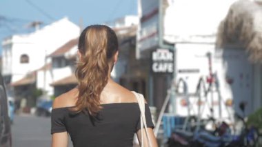 Avrupalı bir kız Sri Lanka 'da sessiz bir caddede yürüyor, ağır çekimde. Kasaba çevresindeki turizm kavramı