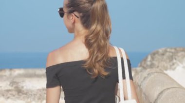 At kuyruklu bir kız dünya mirası sahasında yürüyor ve manzaranın tadını çıkarıyor, ağır çekimde. Tarihi bir ortamda seyahat kavramı