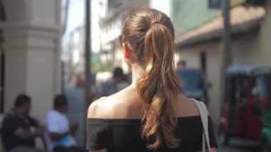 Avrupalı bir kız Sri Lanka 'da sessiz bir caddede yürüyor, ağır çekimde. Kasaba çevresindeki turizm kavramı