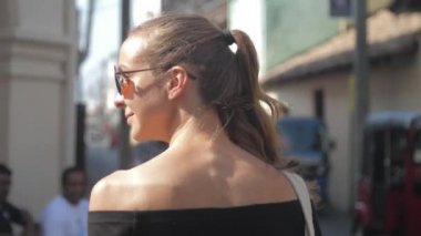 Avrupalı bir kız Sri Lanka 'da sessiz bir caddede yürüyor, ağır çekimde. Kasaba çevresindeki turizm kavramı
