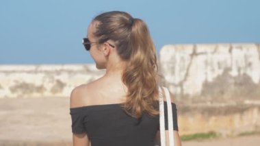 At kuyruklu bir kız dünya mirası sahasında yürüyor ve manzaranın tadını çıkarıyor, ağır çekimde. Tarihi bir ortamda seyahat kavramı