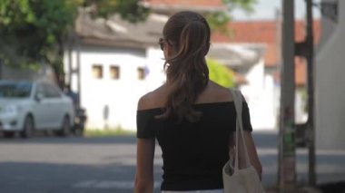 Avrupalı bir kız Sri Lanka 'da sessiz bir caddede yürüyor, ağır çekimde. Kasaba çevresindeki turizm kavramı