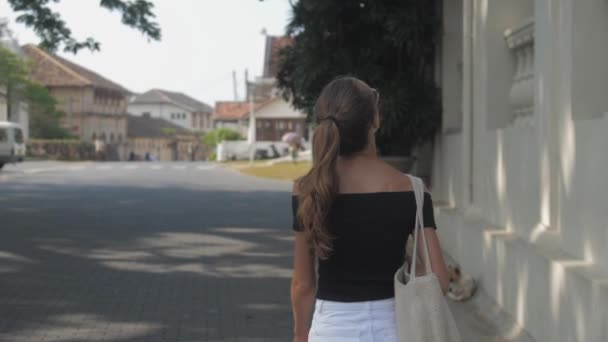 欧洲女孩正沿着斯里兰卡热带城市安静的街道走着 动作缓慢 城市环境中的旅游概念 — 图库视频影像