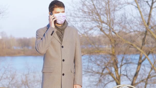 Uomo Europeo Maschera Medica Sta Parlando Smartphone Nel Parco Cittadino — Video Stock