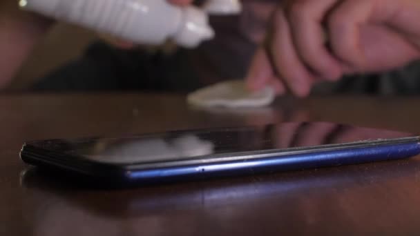 Gros plan d'une personne qui désenfante un smartphone avec un antiseptique 