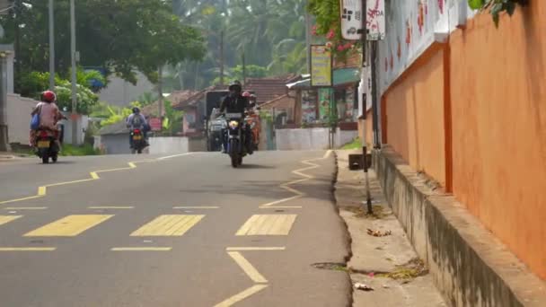 Vehículo conduce a lo largo de la carretera cerca de las casas en día caliente en la isla — Vídeo de stock