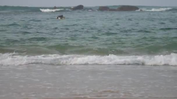 Persona en las velas de tabla de surf en el océano tormentoso con ganas de hacer deporte acuático contra grandes piedras distantes cámara lenta — Vídeos de Stock