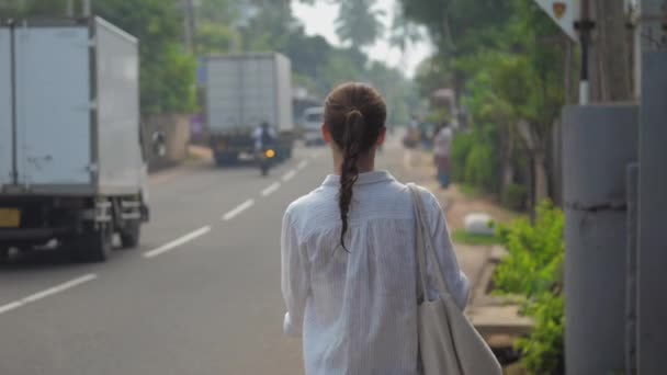 Flicka turist promenader längs gatan väg mot tropisk natur — Stockvideo