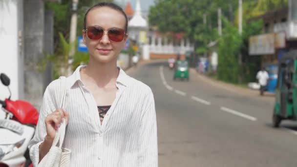 Woman traveler walks along roadside past driving mototaxi — Stock Video