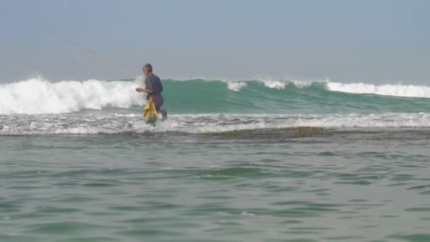 Nehybný stařec stojí ve vodě drží hnědý rybářský prut — Stock video