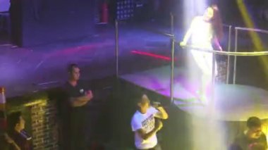 Guy Clubber mikrofona şarkı söylüyor ve kız şarkıcı sahnede dans ediyor.