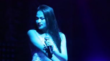 Dantelli pop şarkıcısı kız podyumda şarkı söylüyor.