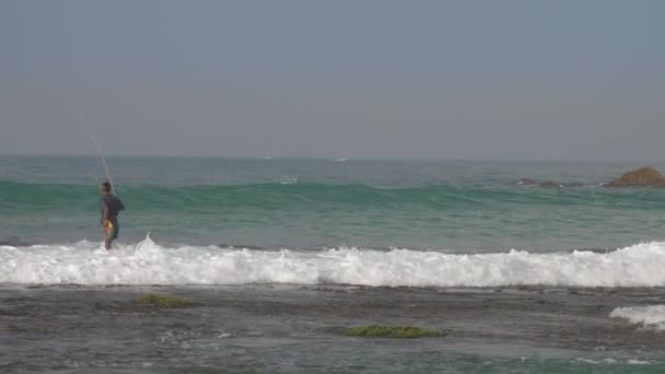 Ψαράς περπατά κατά μήκος του νερού surf άκρη σε αφρώδη κύματα του ωκεανού — Αρχείο Βίντεο