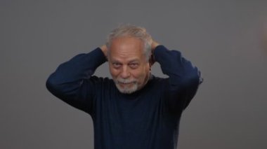 Mavi kazaklı bunalımlı adam gri saçlara dokunuyor.