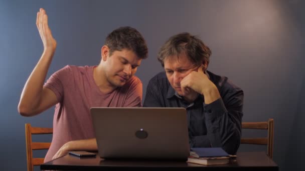 Syn mluví se starším otcem vysvětlující, jak pracovat na notebooku — Stock video