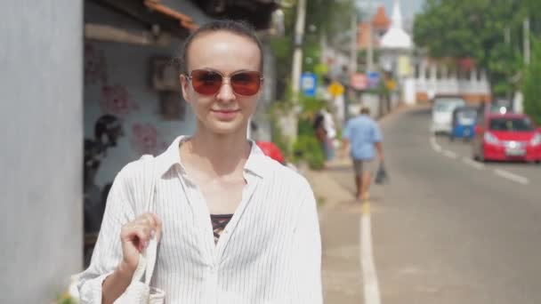 Woman traveler walks along roadside past driving mototaxi — Stock Video