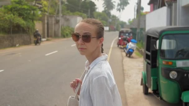 Girl crosses road walking against tropical landscape — Stock Video