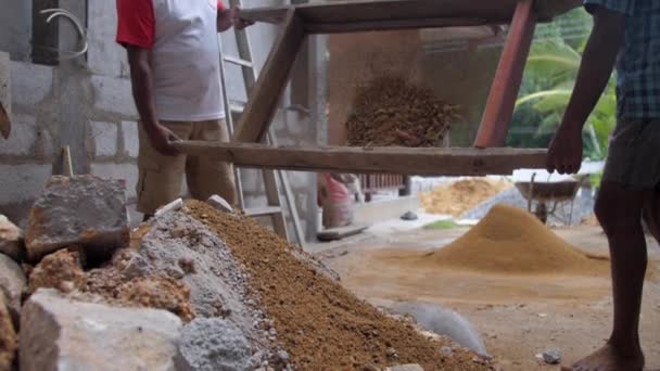 Construction workmen throw away waste from large sieve — Stock Video