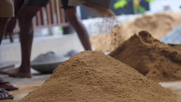 Person grabs yellow sand and throws on pile with shovel — Stock Video