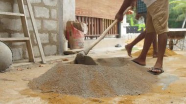 Yerel inşaat işçisi çimento ve kumu birbirine karıştırıyor