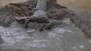 İnsan çimento yığınına şeffaf su döker.