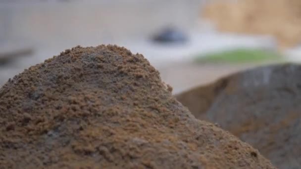 Человек смешивает серый цемент и желтый песок с деревянной лопатой — стоковое видео