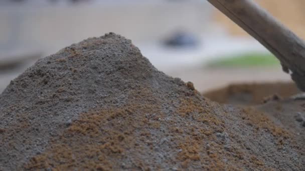 Kişi gri çimento ve sarı kumu tahta kürekle karıştırır. — Stok video