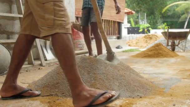 Local construction worker mixes cement and sand close — Stock Video