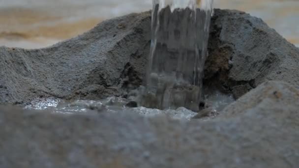 Людина наливає прозору воду в цементну купу близько — стокове відео