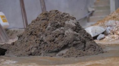 İnsan ıslak çimentoyla yerdeki metal küreği karıştırır.