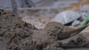Profesyonel inşaat işçisi ıslak gri çimentoyu karıştırıyor