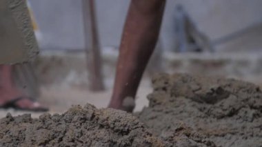 Profesyonel inşaat işçisi ıslak gri çimentoyu karıştırıyor