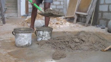 Yerli adam inşaat sepetine gri çimento topluyor.