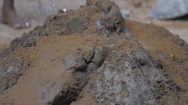 Вода падает на цементную кучу с желтым песком перед смешиванием — стоковое видео