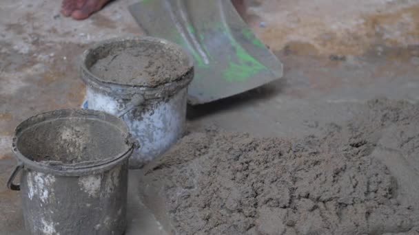 Travailleur met du ciment humide dans de vieux seaux avec une pelle métallique — Video