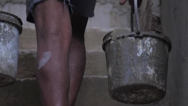 A piedi nudi lavoratore locale trasporta vecchi secchi con cemento bagnato — Video Stock