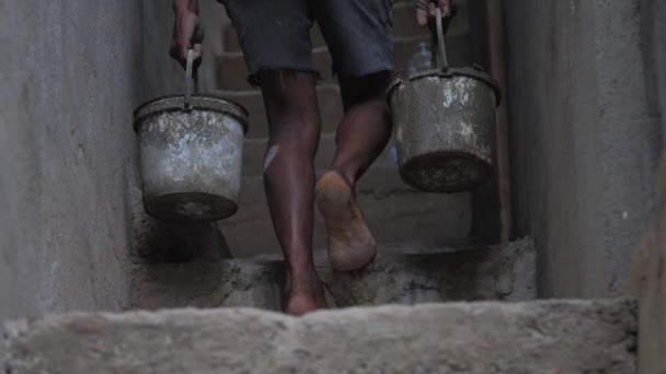 Barefoot local worker carries old buckets with wet cement — Stock Video