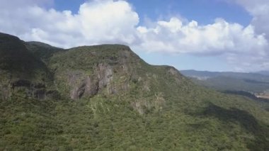 Gökyüzüne karşı küçük bir ülkeye yakın yemyeşil bitki örtüsü olan bir dağ.