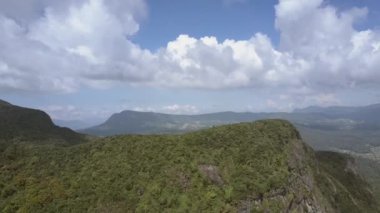 Gökyüzüne karşı küçük bir ülkeye yakın yemyeşil bitki örtüsü olan bir dağ.