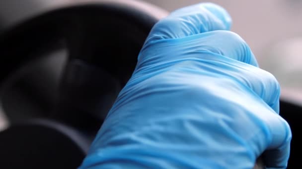 Человек в синих стерильных перчатках держит черное руль — стоковое видео