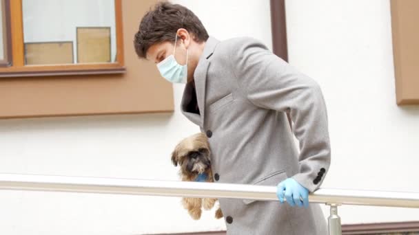 Bacağı yaralı bir adam elinde küçük bir köpekle hastaneye yürür. — Stok video